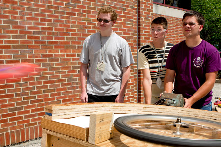 Three male Catapult students testing their Frisbee throwing device.