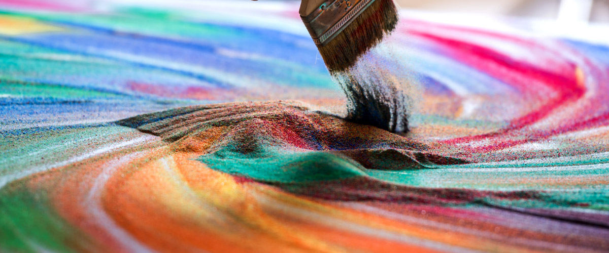 Colored sand being swept by a paint brush