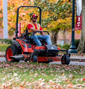 Man on a mower on campus.