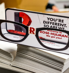 Image shows a pair of “nerd glasses” made of paper and sent to newly admitted students. 