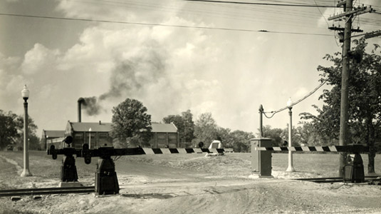 Historical photo showing front entrance to Rose Polytechnic with interurban railroad crossing in foreground.