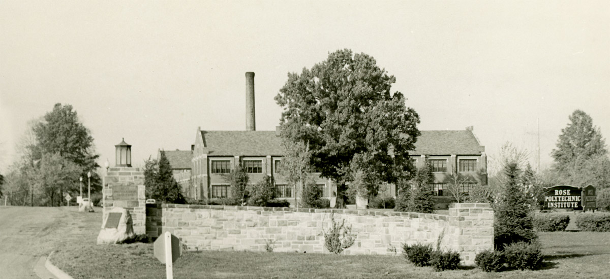 Historical black and white photo of the main campus entrance.
