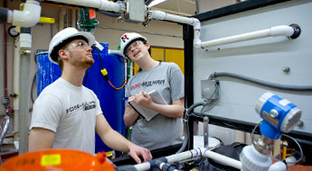 Two male students work in chemical engineering lab.