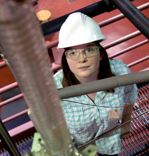 Female student wearing hard hat works in High Bay Lab.