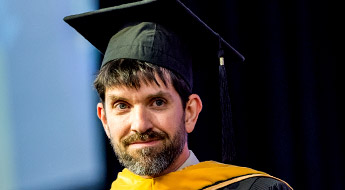 !Image shows a professor smiling and wearing academic gowns during Rose-Hulman’s graduation ceremony.