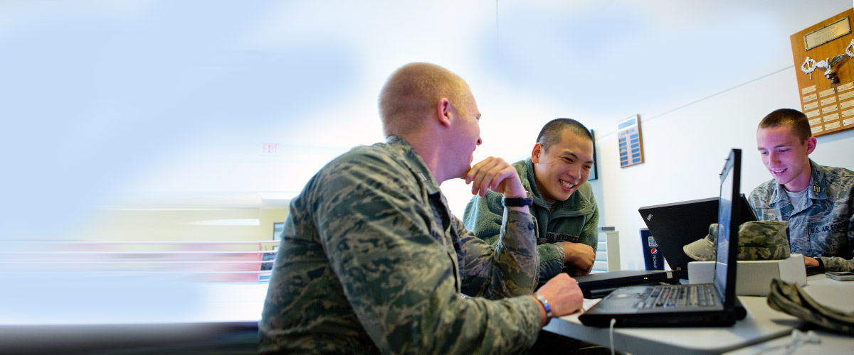 Members of the ROTC program sit around laptops and smile.