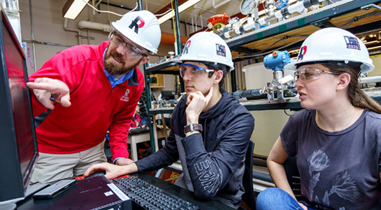 !Students wearing a Rose-Hulman hardhat working in a research lab.