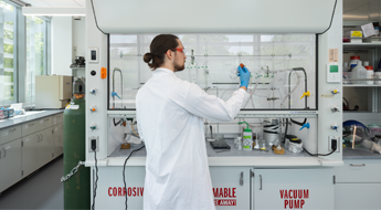 Female student wearing latex gloves mixes liquids in a laboratory.
