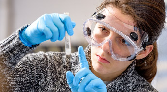 Male student scoops dry chemical ingredient for experiment.