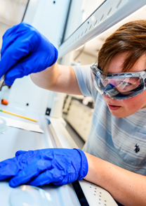 Male student uses dropper to add liquid to test tube.