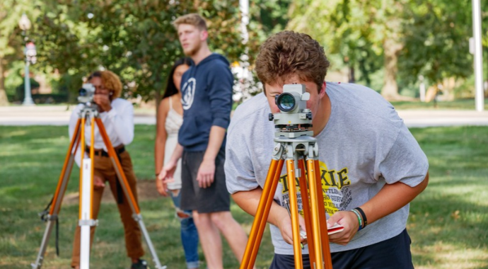 Student works with piece of equipment outside.