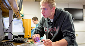 Male student works at computer station in electrical engineering lab.