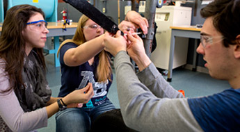 A male student and two female students work together in a hands-on activity.