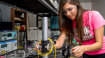 Female student works with device in physics lab.