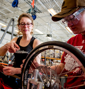 A female student and a male student make adjustments to the team’s efficient vehicle.