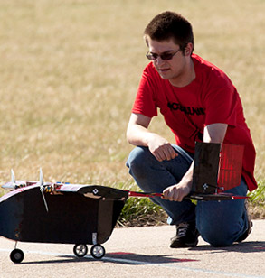 Male student holds onto remote control aircraft.