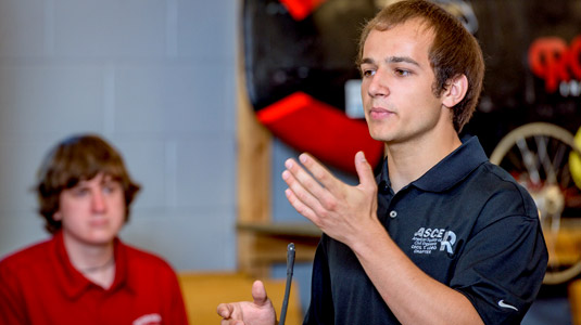 Student gives presentation on Grand Challenges project at media event.