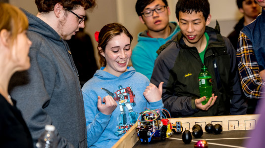 Smiling students take part in a robotics competition.