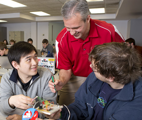 Dr. David Fisher works with students on a laptop computer.