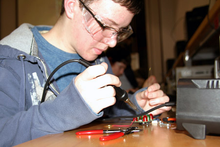 Student solders wires to a circuit board.