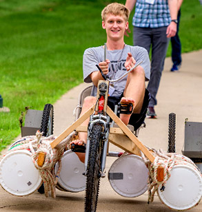 A male student rides a three-wheeled amphibious vehicle created during Operation Catapult