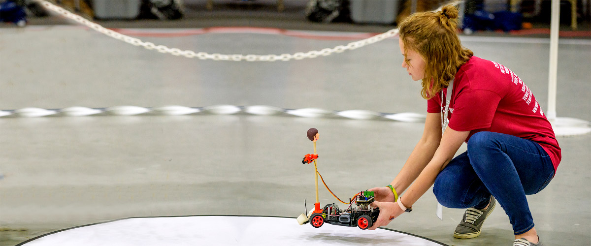 A female student readies her autonomous vehicle to race.