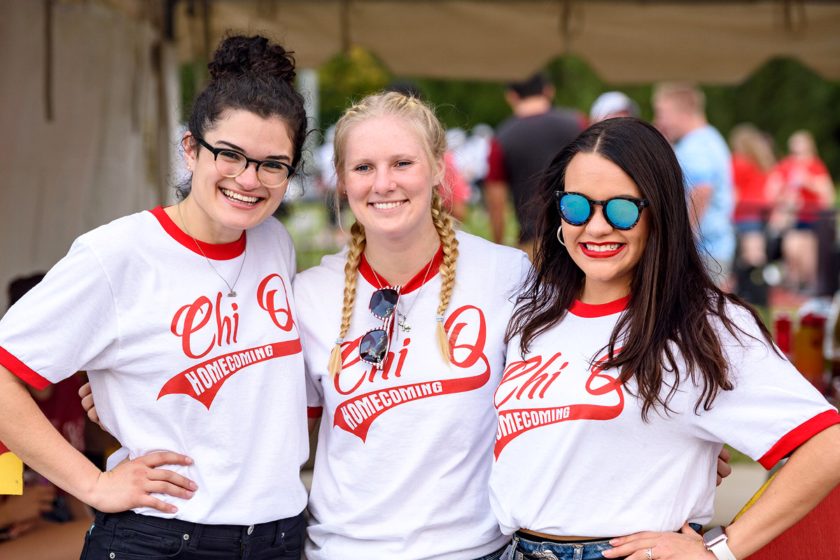 Three females wearing Chi Omega t-shirt at Homecoming