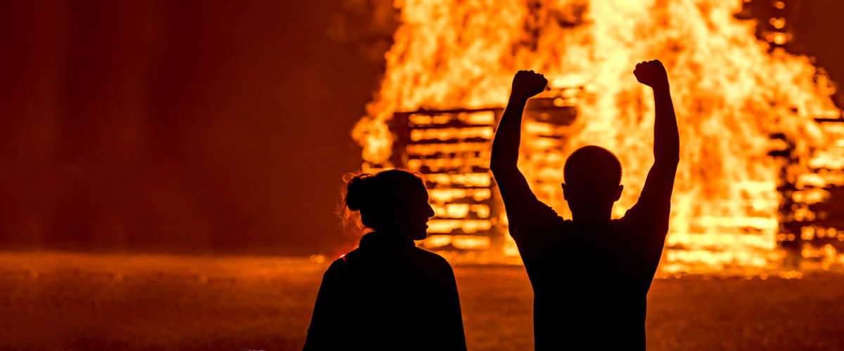 !homecomming bonfire with students silhouetted in the light of the flame