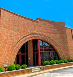 !Brick and glass exterior of Olin Hall under a bright blue sky.