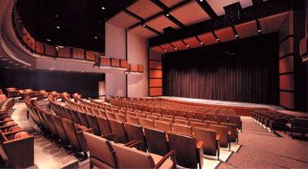 !The Hatfield Hall Theater and stage. The image shows several rows of seats and the curtain drawn on the stage.
