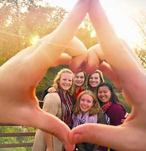 Members of the Panhellenic Council smiling and framed by two hands making a heart shape.