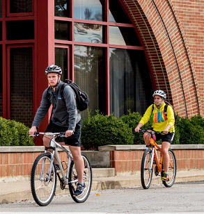 Two students riding bicycles on campus.