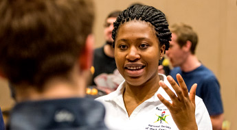 Female student smiles and gestures while talking to another student.
