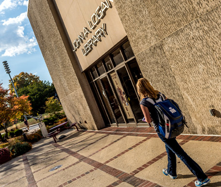 Female student walking in front of the John A. Logan Library.