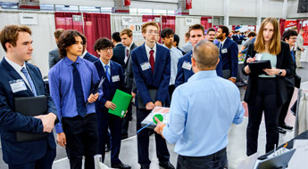 An employer speaks to a student and holds their resume at the Career Fair.