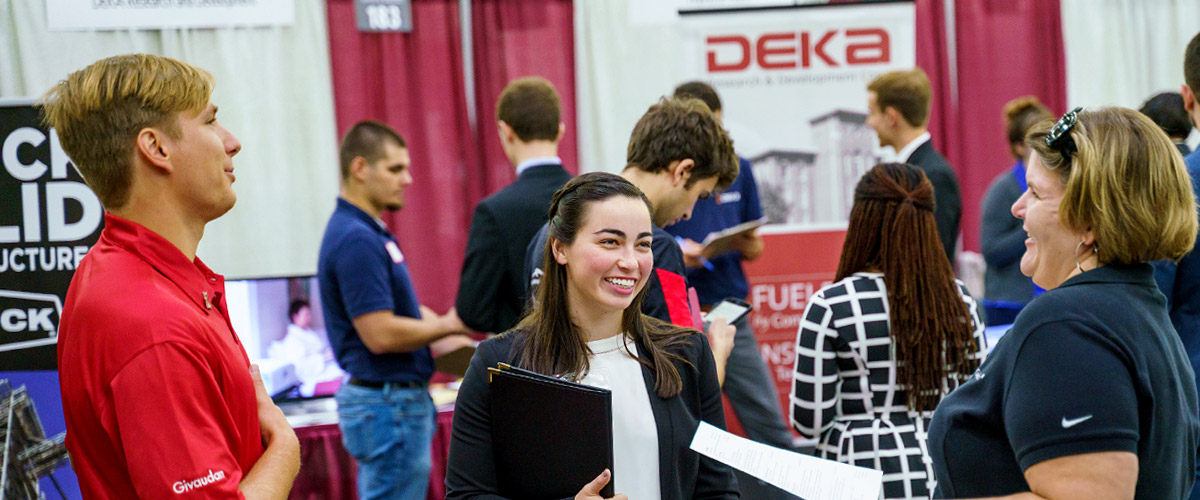 Smiling student meets with recruiters at Career Fair.