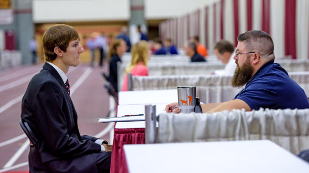 Student shaking a recruiters hand at career fair.