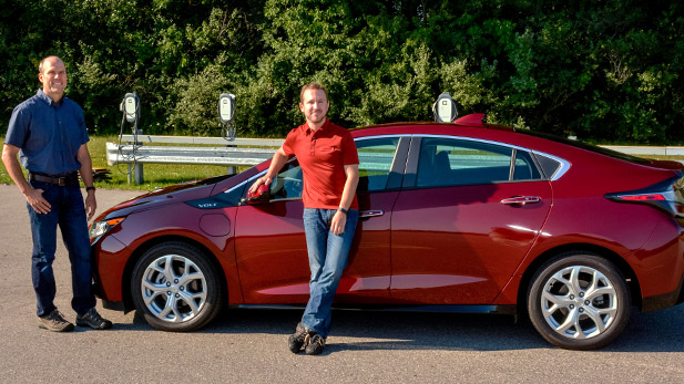 Greg Hubbard and Anthony Heap stand in front of an electric car.