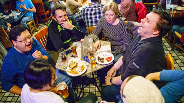 Male and female professors sitting around a table laughing and talking at Sonka Irish Pub.