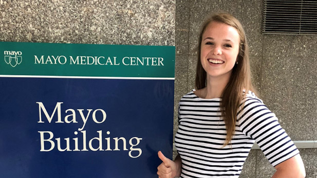 Bailey MacInnis stands next to a sign reading "Mayo Medical Center"