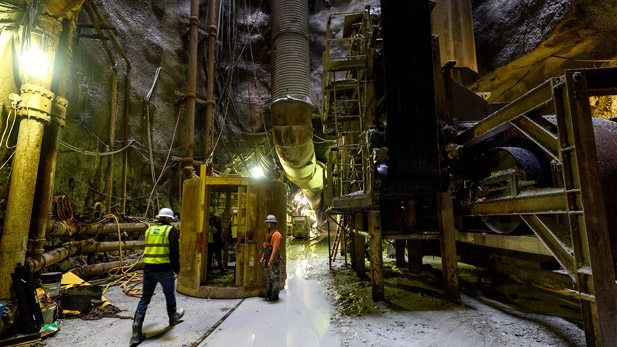 View of workers and machinery operating in a large underground tunnel