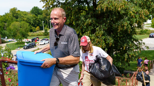 President Coons carrying a tote of new student belongings up the stairs to Mees Hall.