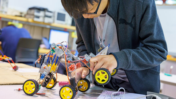 A student working on a wheeled robotic device.