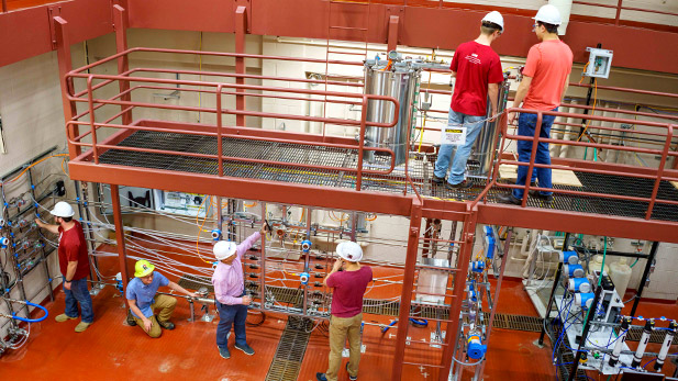 Image shows students wearing hard hats working in chemical engineering's two-story high bay lab inside Olin Hall. 