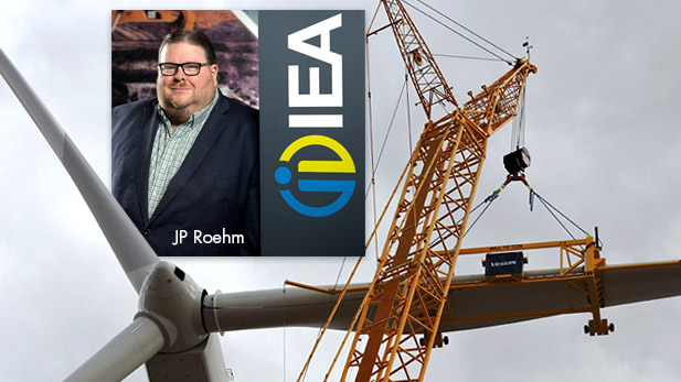 Image shows image of JP Roehm superimposed on a photo of a wind turbine construction project.