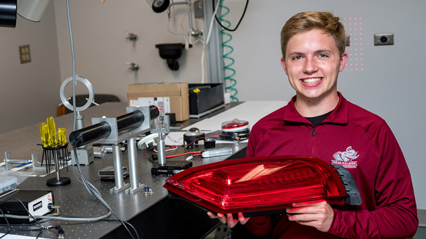 Cody Brelage holding the large, red automotive light that earned outstanding project honors.