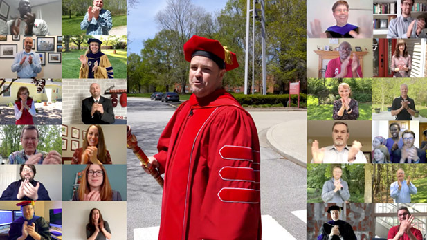Image shows Erik Hayes in center of screen in his graduation regalia. On either side are video chat screens showing about 20 faculty and staff members applauding the graduates.