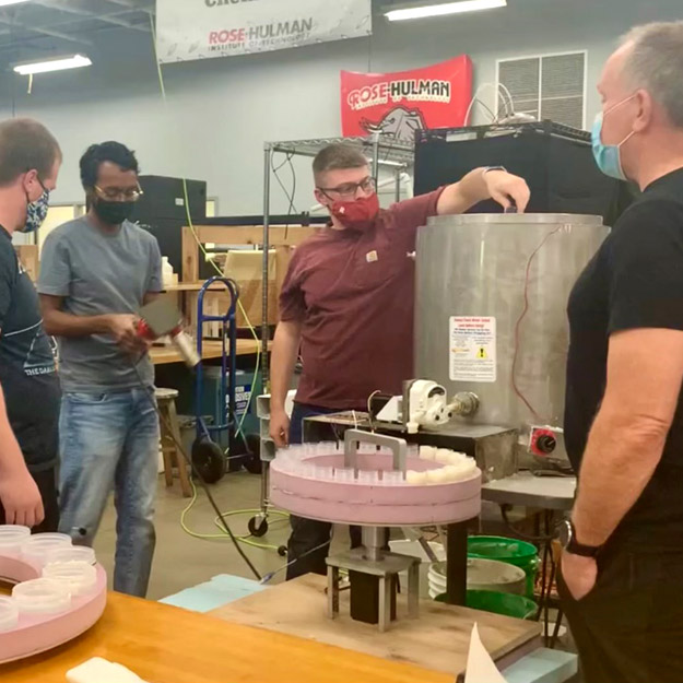 Image shows four students talking with company owner inside a Rose-Hulman innovation space.