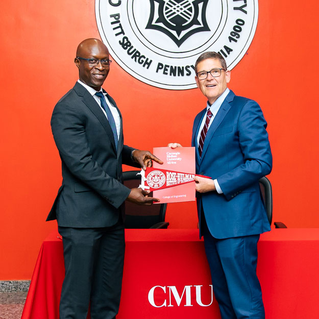 Conrad Tucker and Rick Stamper jointly holding print materials from Carnegie Mellon University Africa
