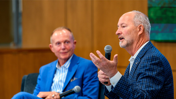 Steve Hill and President Robert A. Coons both sit in front of an audience in the Lake Room, each holding a microphone.